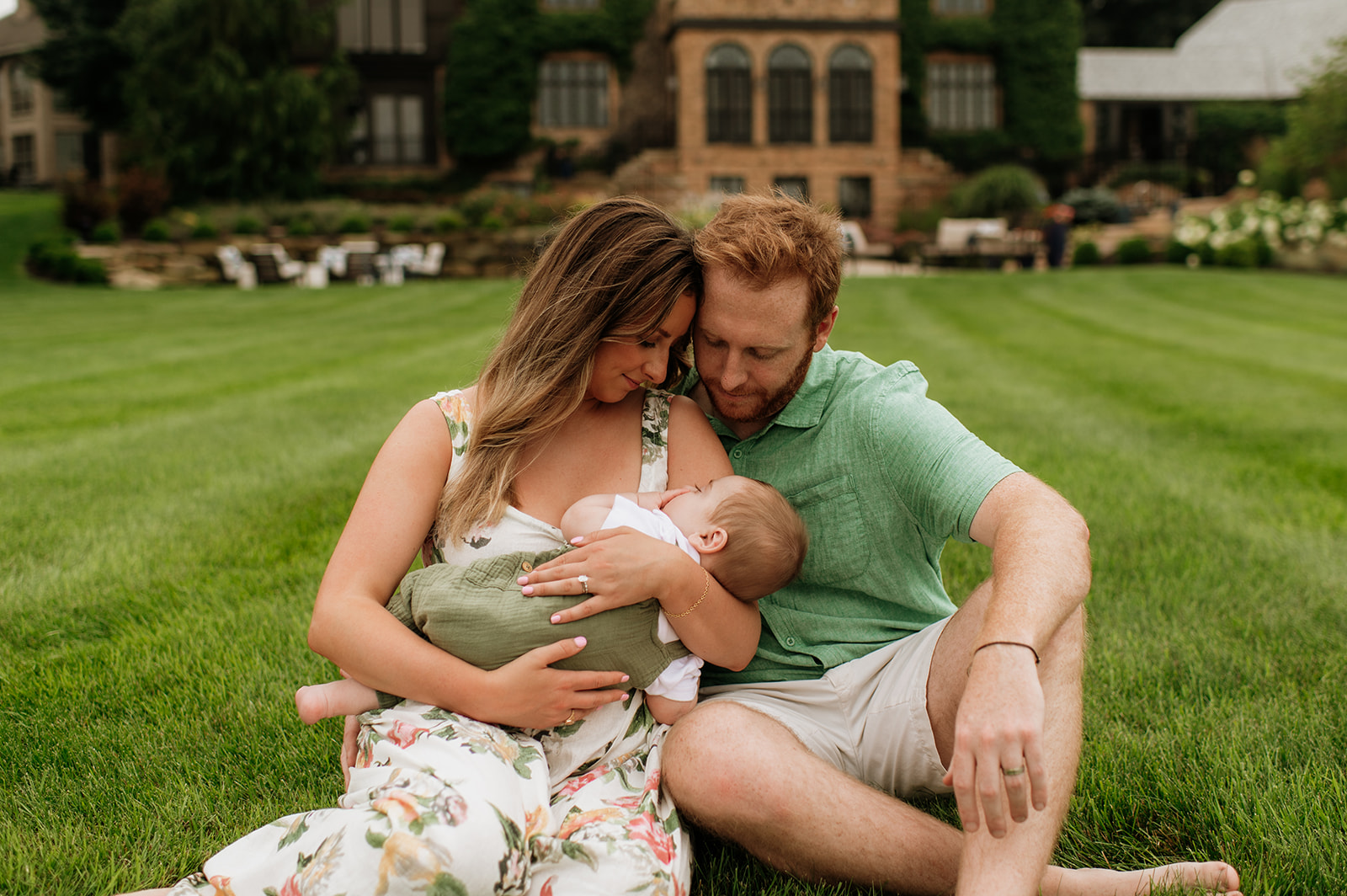 Mother and father holding their newborn baby while he takes a nap during their Lake Michigan family photos in Holland