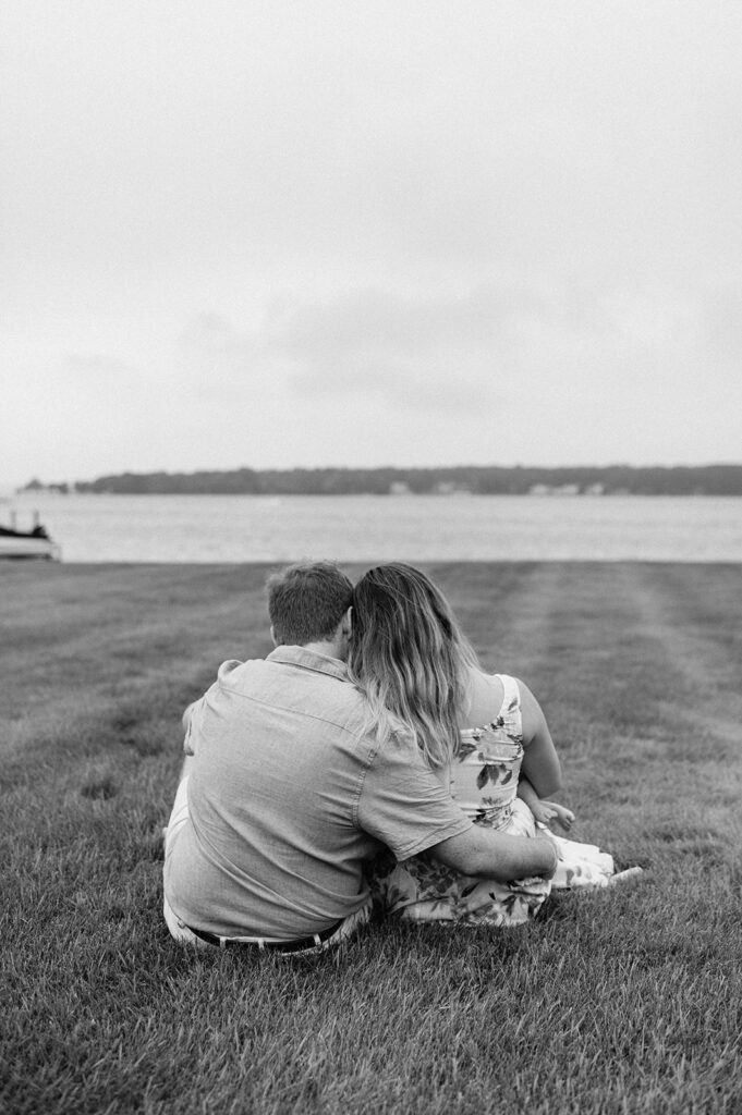 Black and white photo of a man and woman sitting together with their newborn baby during their Lake Michigan family photos in Holland