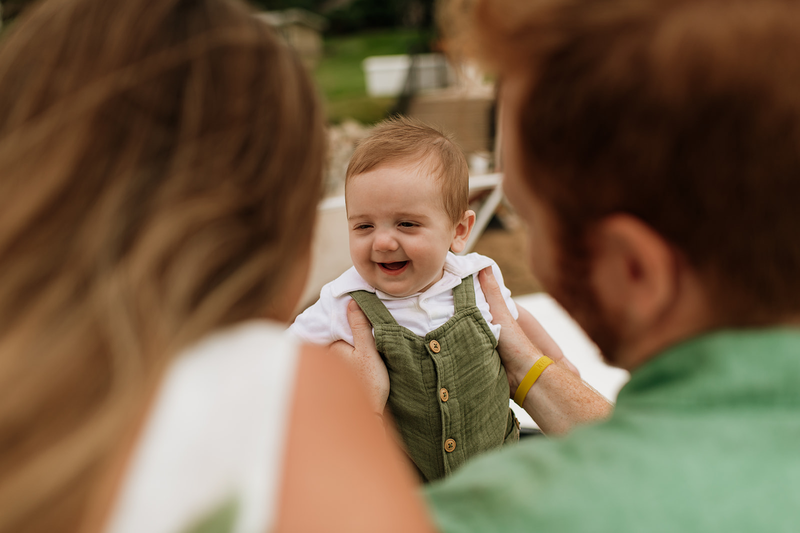 Baby smiling while his mother and father admire him