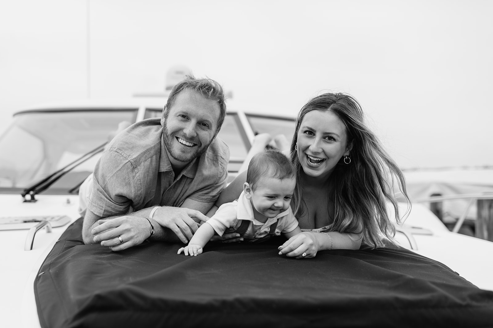 Black and white photo of a family of three posing for their Lake Michigan family photos on a boat