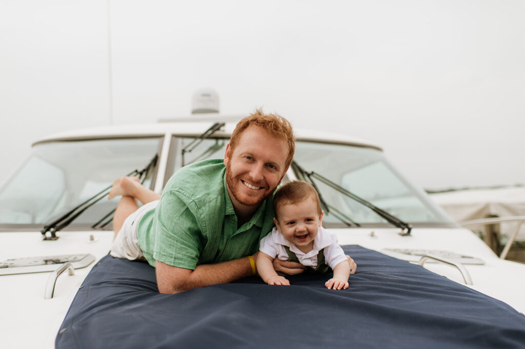 A father laying with his baby on a big during their Lake Michigan family photos in Holland