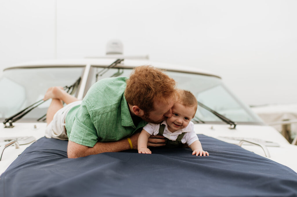 A father laying with his baby on a big during their Lake Michigan family photos in Holland