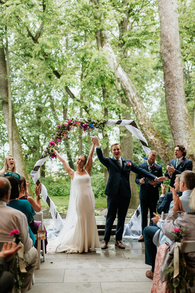 A rainy and colorful outdoor wedding ceremony on the Covered Patio at The Wooded Knot in Tippecanoe, Indiana