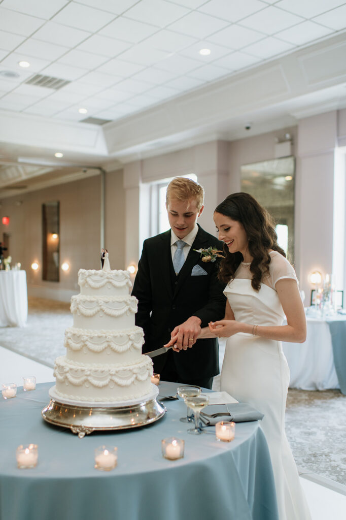 Bride and groom cutting into their wedding cake during their Ritz Charles Carmel, Indiana wedding reception in the Ginkgo Ballroom