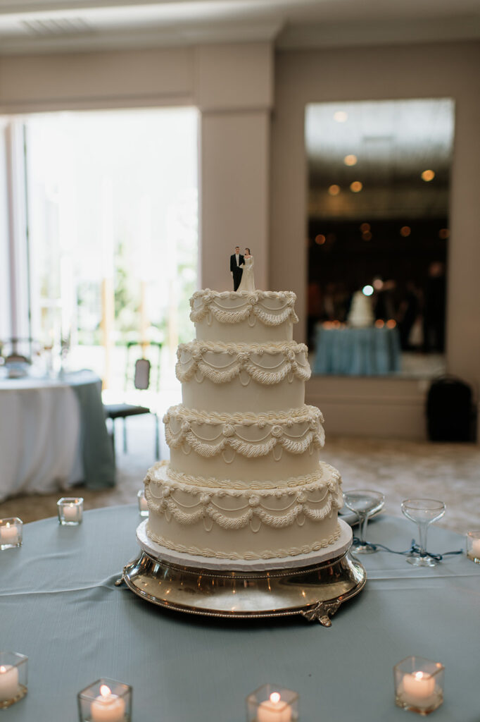 Four-tiered classic white wedding cake with a bride and groom cake topper