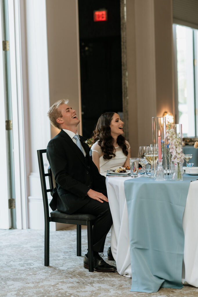 Bride ands groom laughing during their wedding speeches