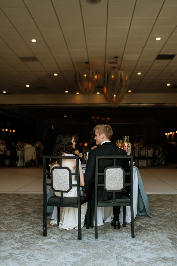 Bride and groom at the sweethearts table during their Ritz Charles Carmel, Indiana wedding reception in the Ginkgo Ballroom