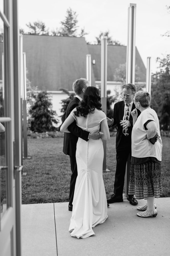 Black and white photo of a bride and groom mingling during their wedding reception