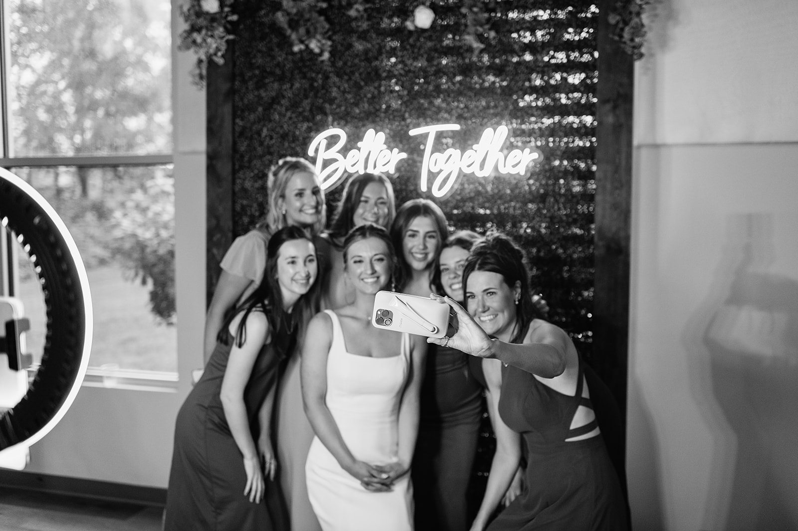 Black and white photo of a bride taking a selfie with guests