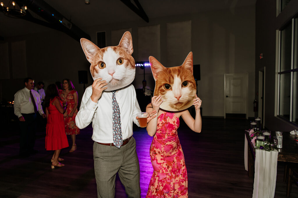 Wedding guests holding up cat face cutouts 