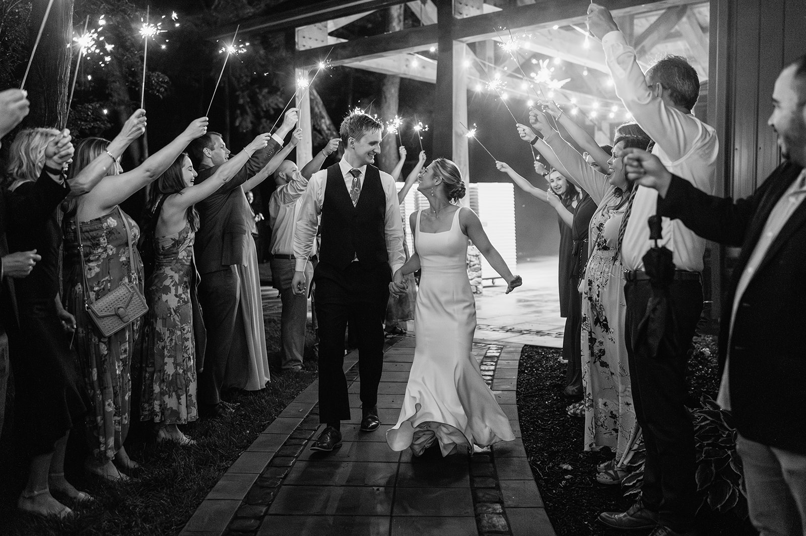 Black and white photo of a bride and groom walking out during their sparkler wedding exit