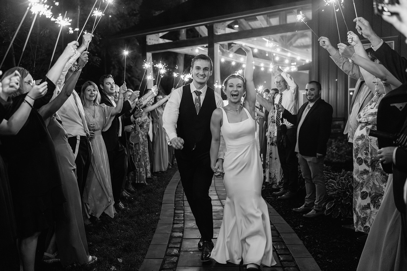 Black and white photo of a bride and groom walking out during their sparkler wedding exit