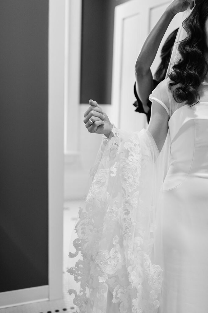 Black and white photo of a bride getting her veil secured