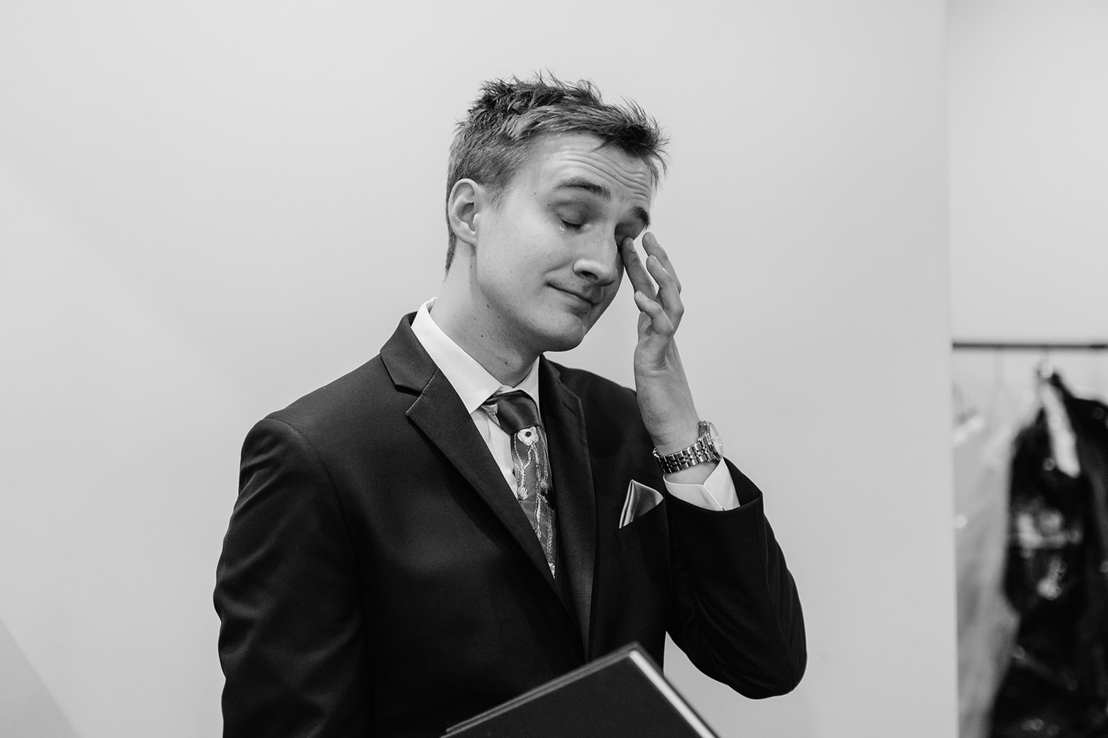 Black and white photo of a groom crying after looking at his gift from his bride