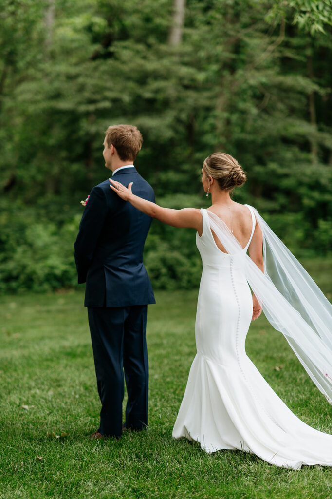 Bride tapping her groom on the shoulder for a first look