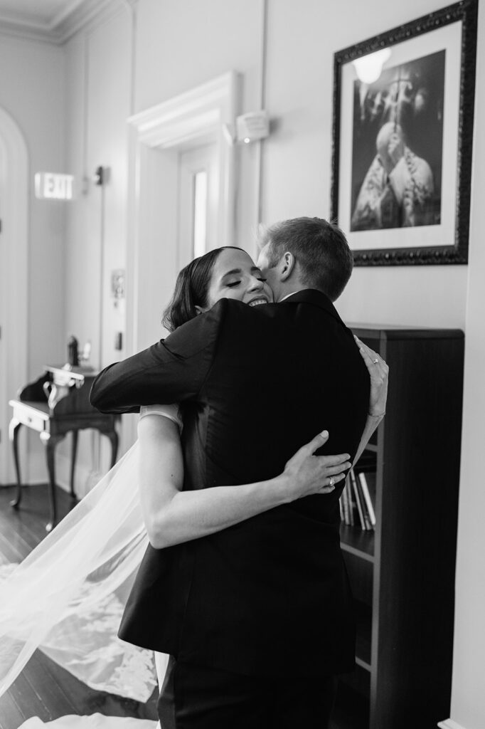 Black and white photo of a bride and groom hugging during their first look