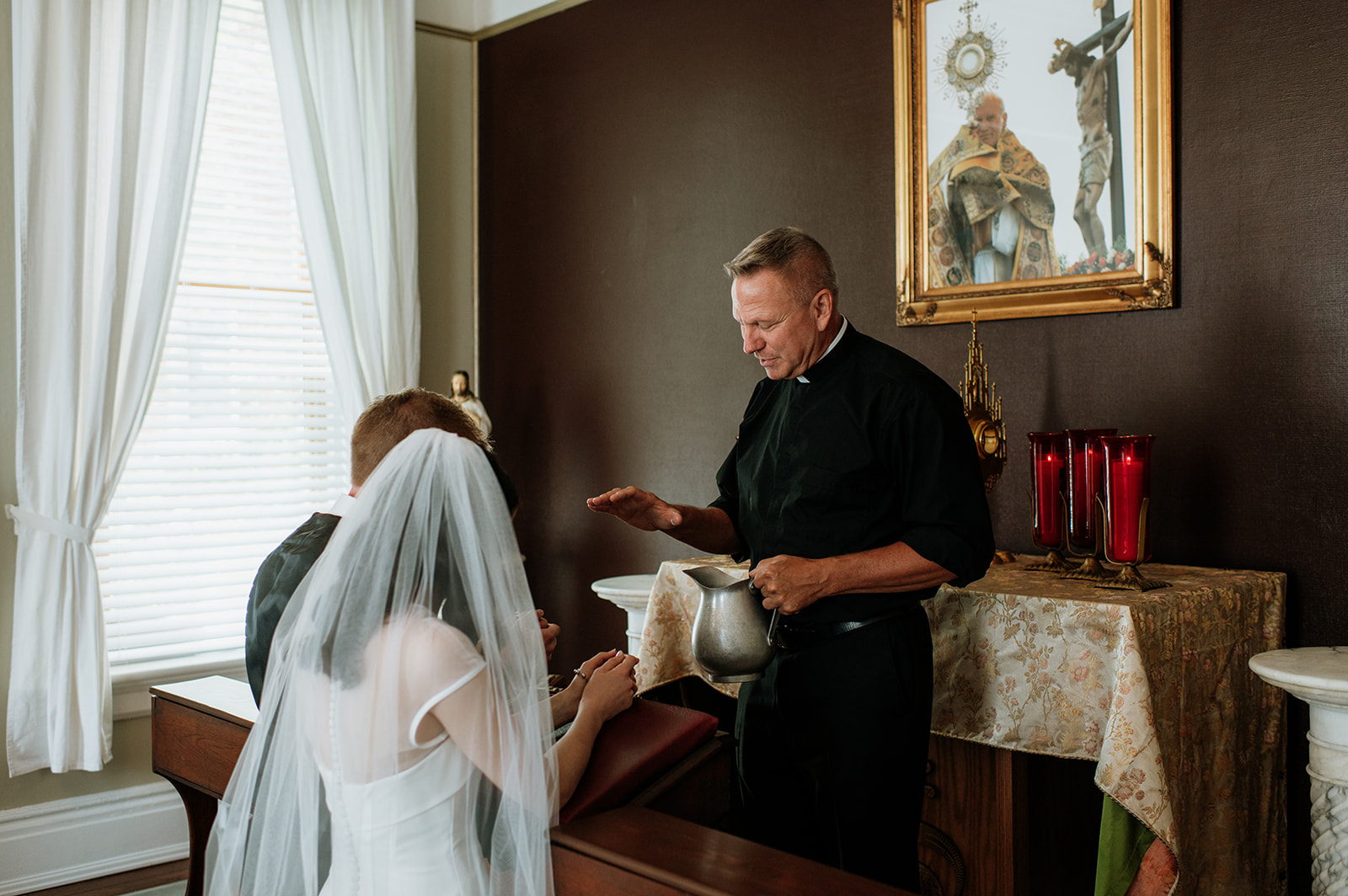 Bride and groom sharing a blessing with the priest before their St. John the Evangelist Catholic Church wedding ceremony in Indianapolis, Indiana