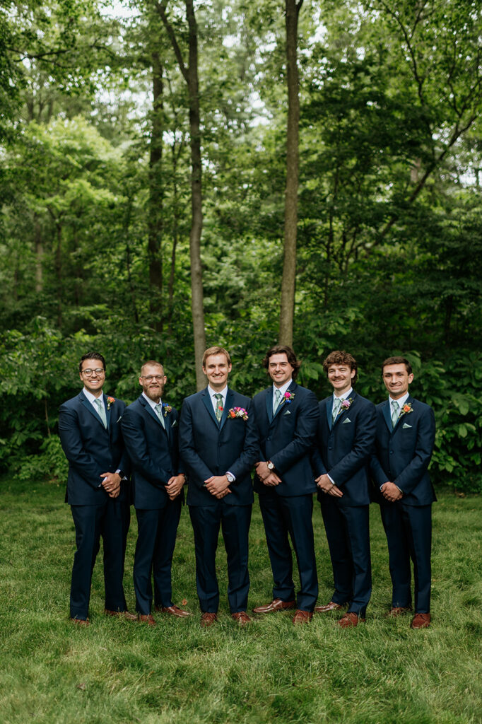 Outdoor groom and groomsmen photos from a colorful wildflower wedding at The Wooded Knot in Tippecanoe, Indiana