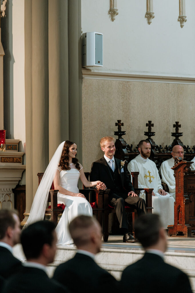 Bride and groom sitting during their St. John the Evangelist Catholic Church wedding ceremony in Indianapolis, Indiana