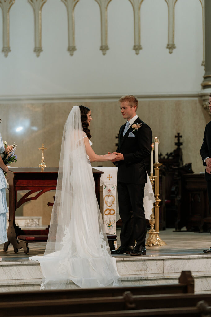 Bride and groom holding hands during their St. John the Evangelist Catholic Church wedding ceremony in Indianapolis, Indiana