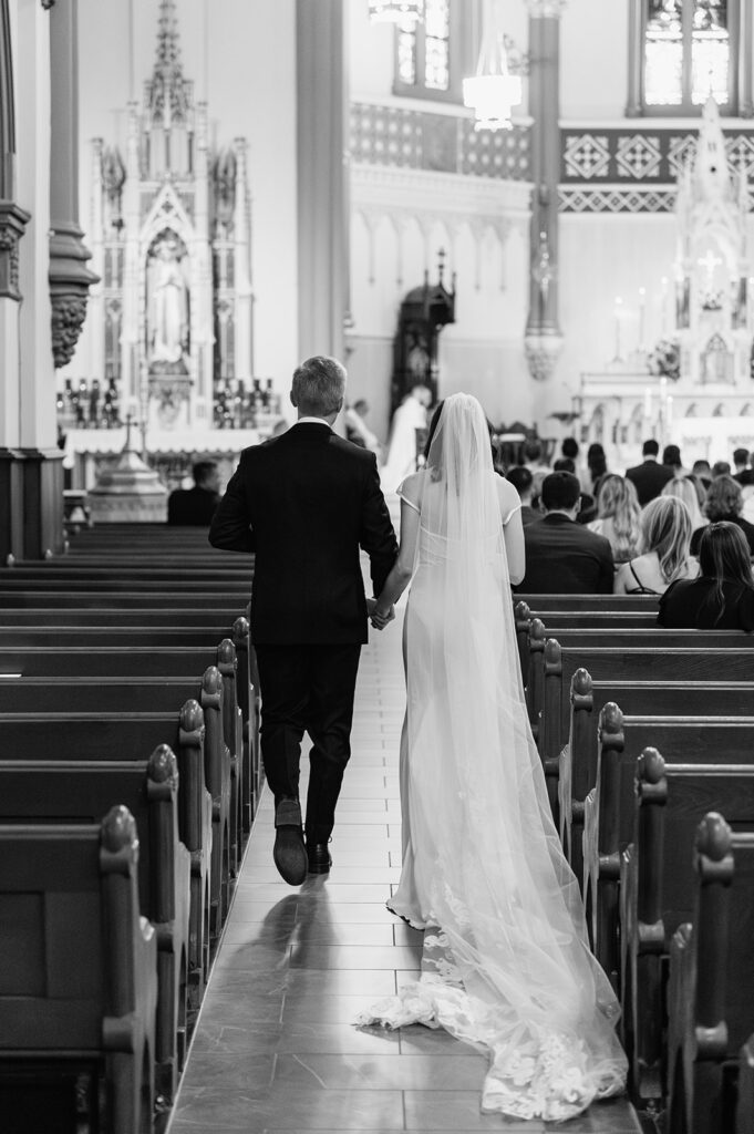 Black and white photo of a bride and groom walking down the aisle during their St. John the Evangelist Catholic Church wedding ceremony in Indianapolis, Indiana