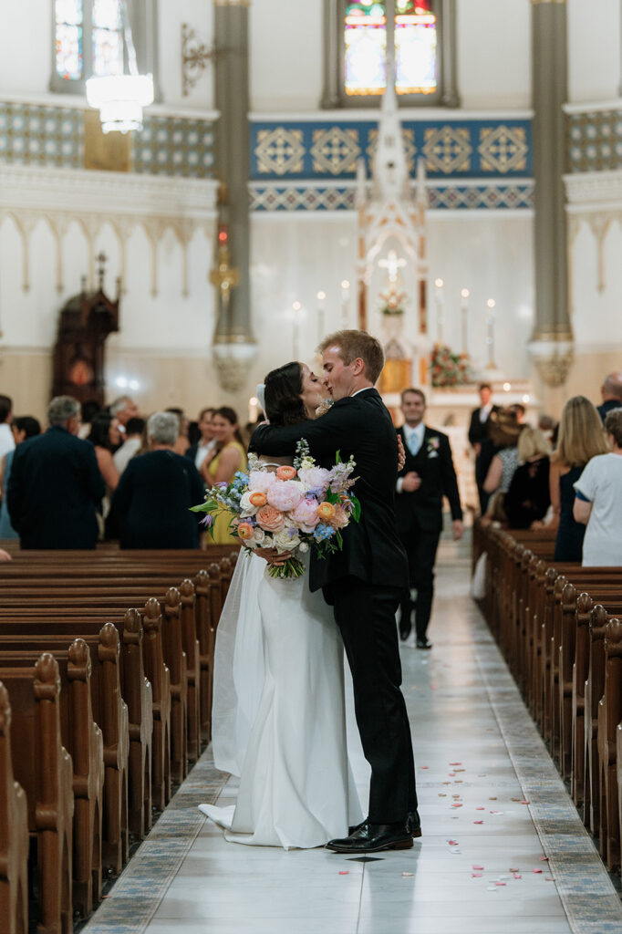 Bride and groom kissing in the aisle during their St. John the Evangelist Catholic Church wedding ceremony in Indianapolis, Indiana