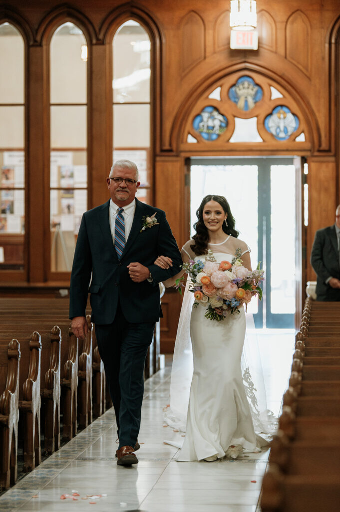 Bride being walked down the aisle by her father for her St. John the Evangelist Catholic Church wedding ceremony in Indianapolis, Indiana