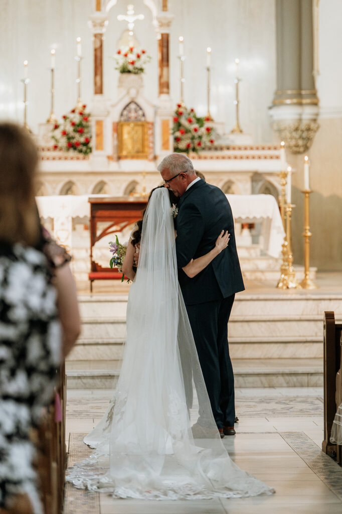 Bride hugging her father at the end of the aisle before her St. John the Evangelist Catholic Church wedding ceremony in Indianapolis, Indiana