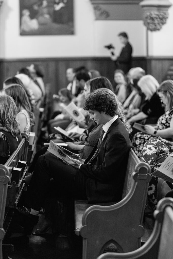 Black and white photo of a wedding guests during a St. John the Evangelist Catholic Church wedding ceremony in Indianapolis, Indiana