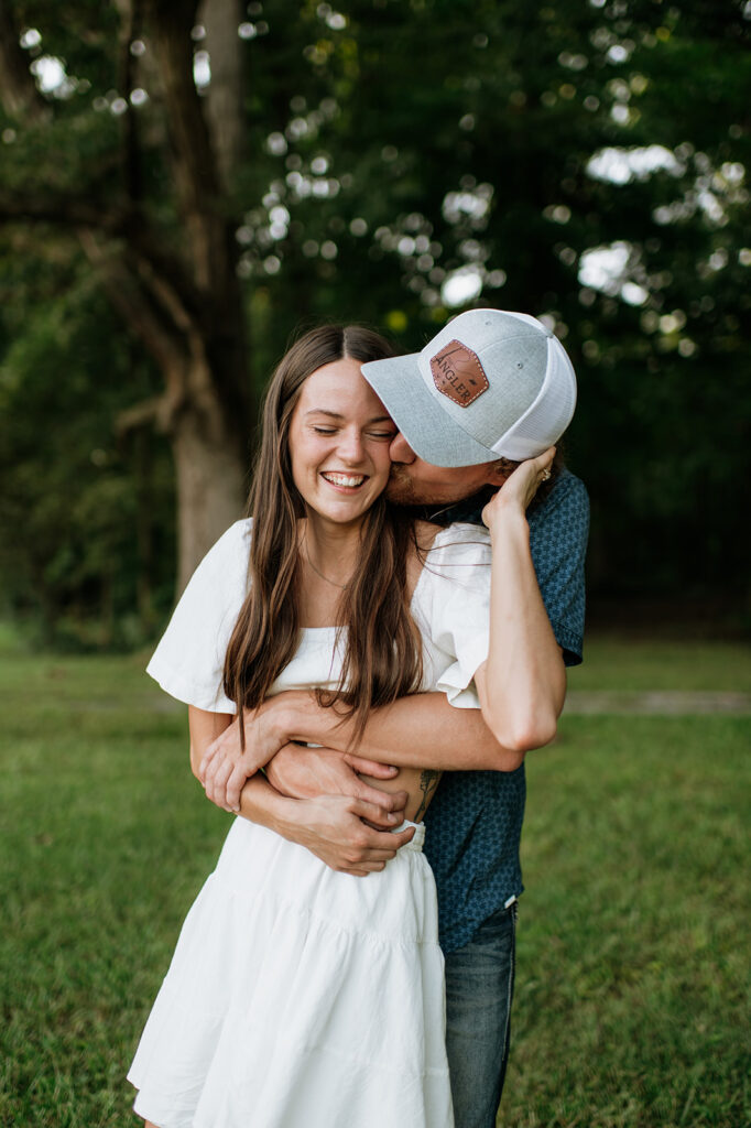 Man kissing his fiancé on the cheek during their outdoor Midwest engagement photos in Albion, Indiana