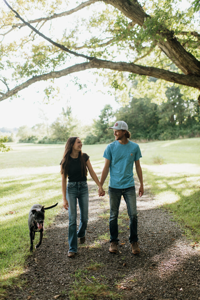 Couple walking down a dirt path with their dog during their Midwest engagement photos in Albion, Indiana