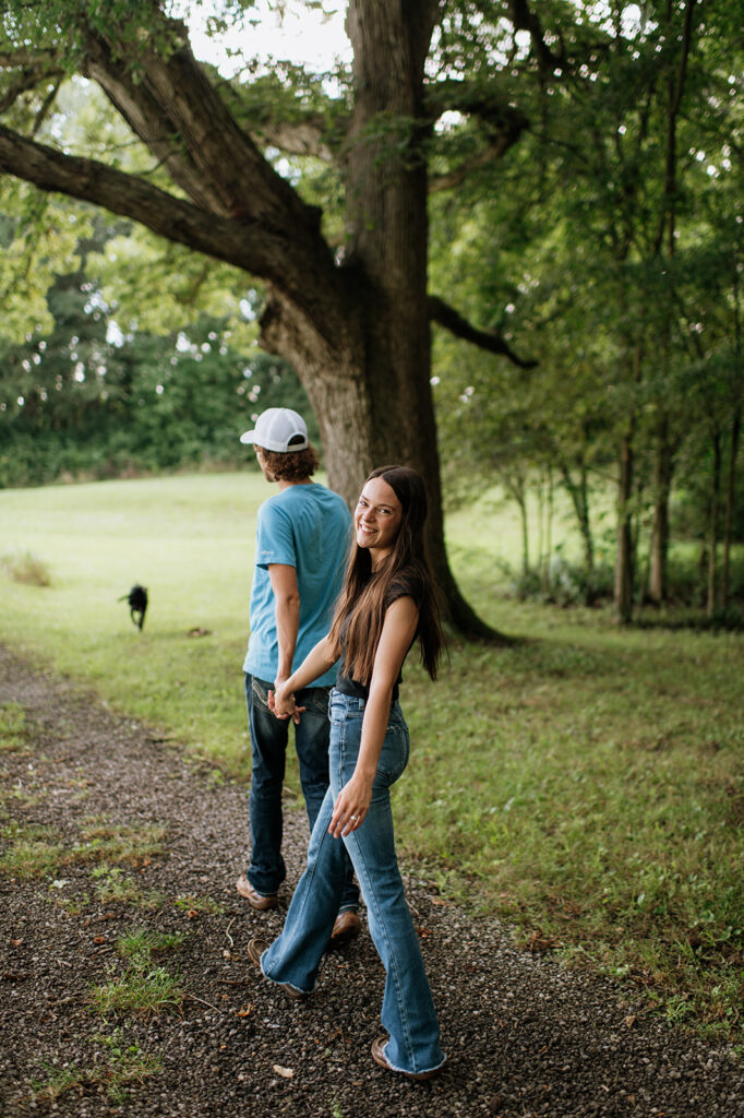 Man and woman holding hands as they walk along a dirt path