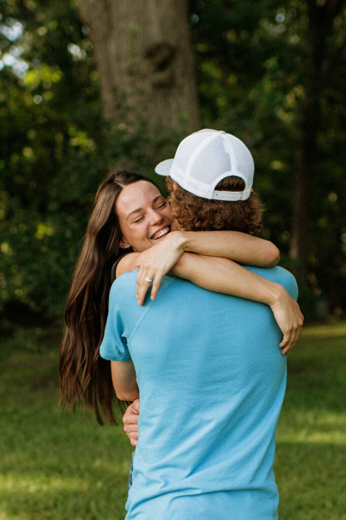 Woman laughing as her fiancé picks her up