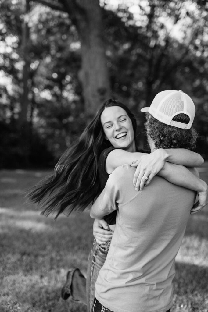 Black and white candid engagement photo of a man and woman being playful