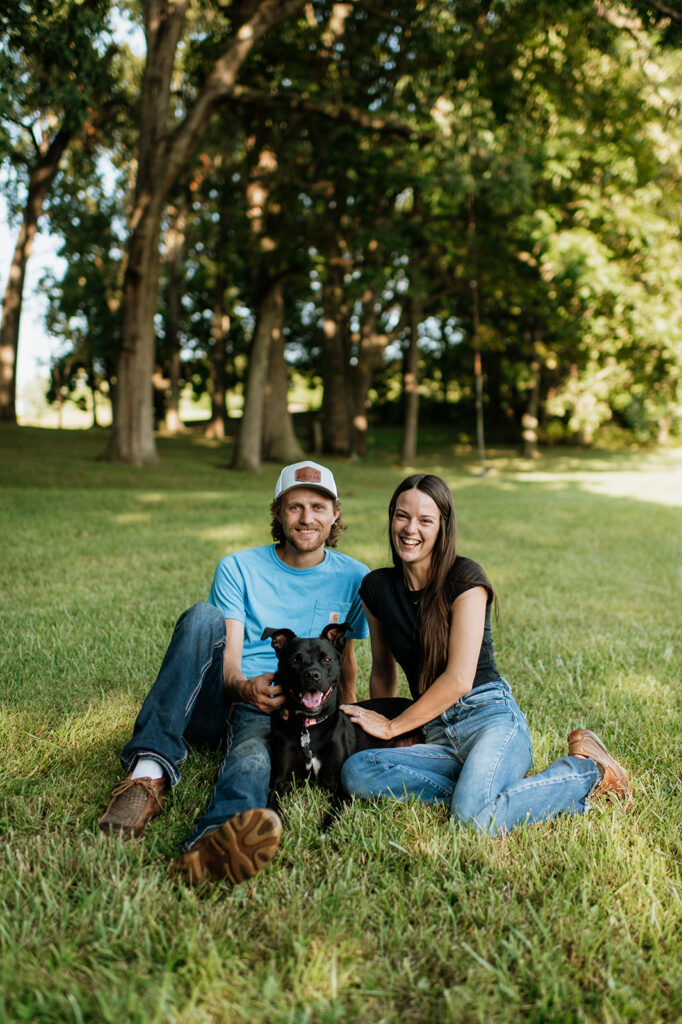 Couple sitting in the grass with their dog for their Midwest engagement photos in Albion, Indiana