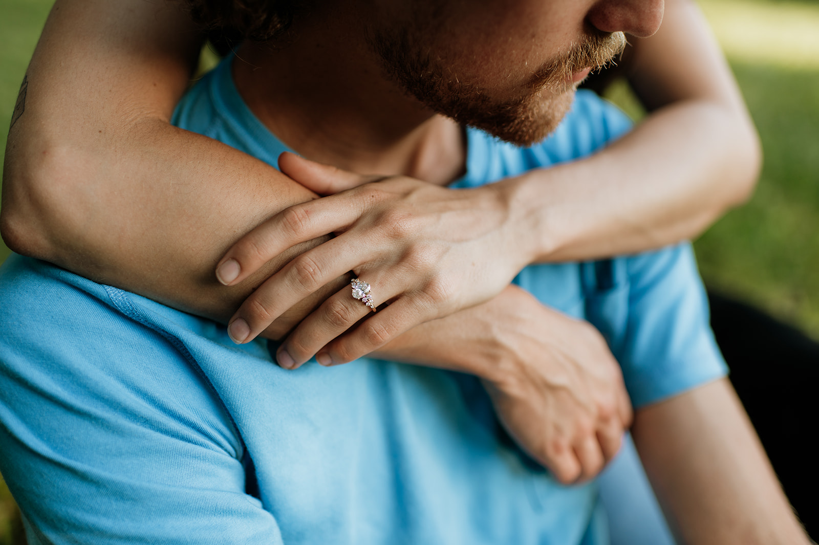 Close crop of a woman with her hands around her fiancé and showing off her engagement ring