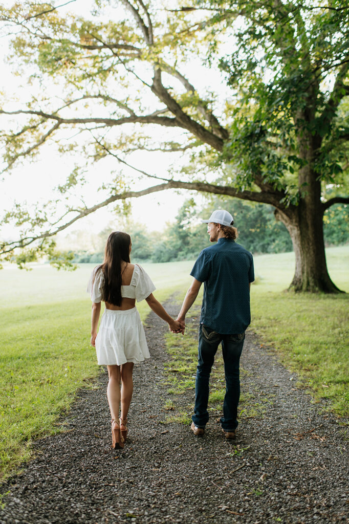 Man and woman holding hands as they walk down a dirt path