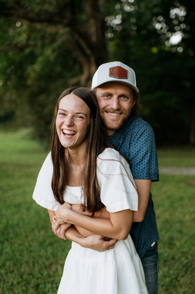 Man hugging his fiancé from behind as she laughs