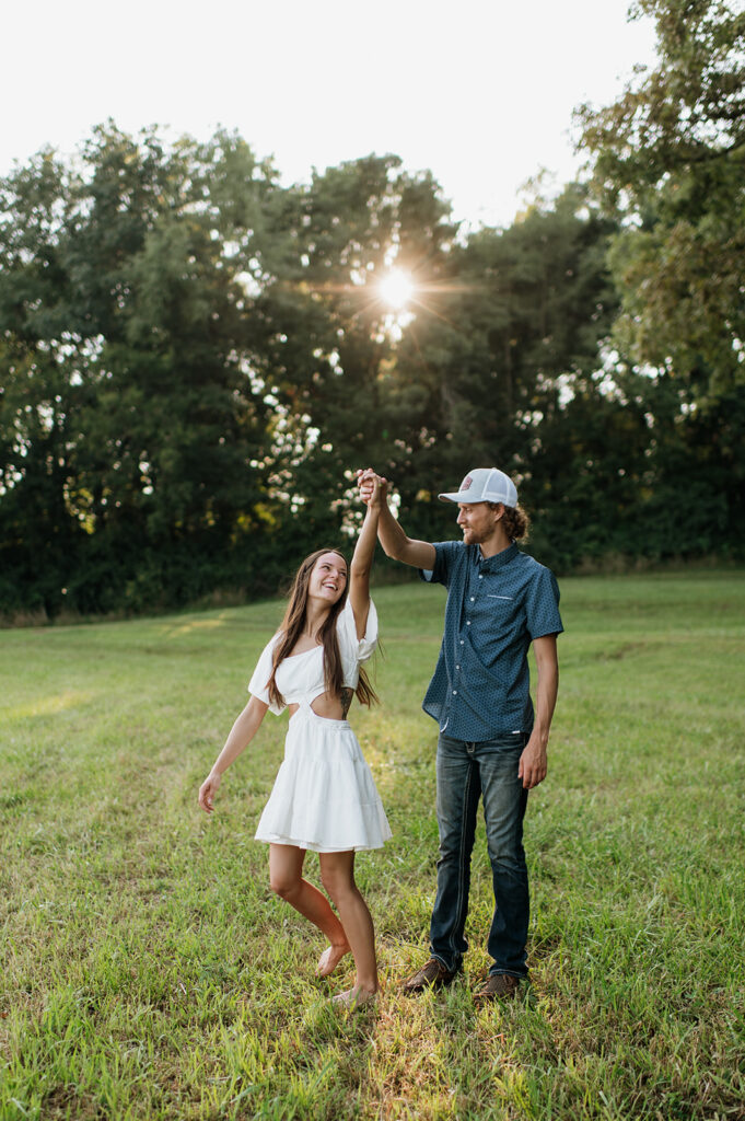 Man twirling his fiancé around at sunset for their Midwest engagement photos