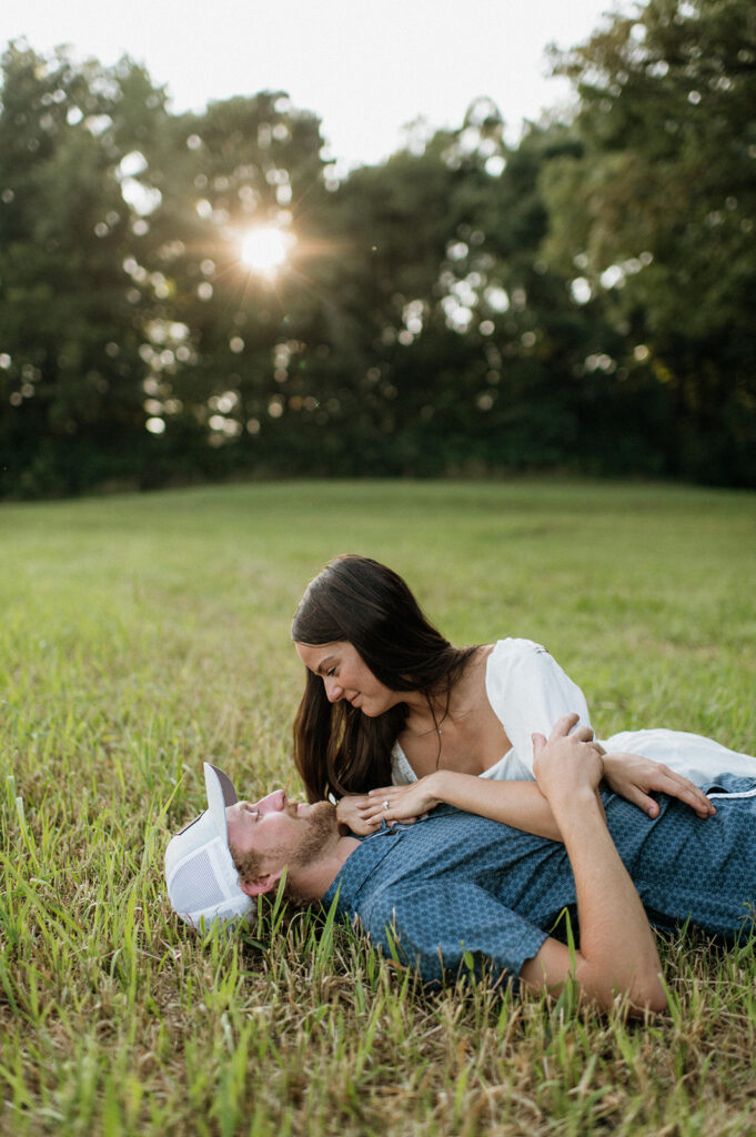 Man and woman laying in an open grassy area for their Midwest engagement photos in Albion, Indiana