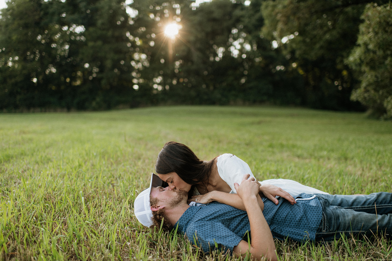 Couple kissing while they lay in the grass for their Midwest engagement photos in Albion, Indiana