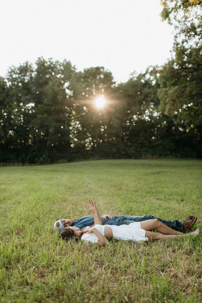 Man and woman laying in an open grassy area for their Midwest engagement photos in Albion, Indiana