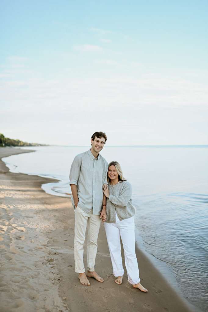 Man and woman posing on Gordon Beach in New Buffalo, Michigan for their engagement photos