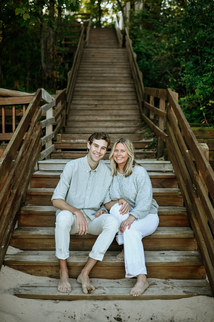 Couple sitting on beach stairs during their New Buffalo engagement photos