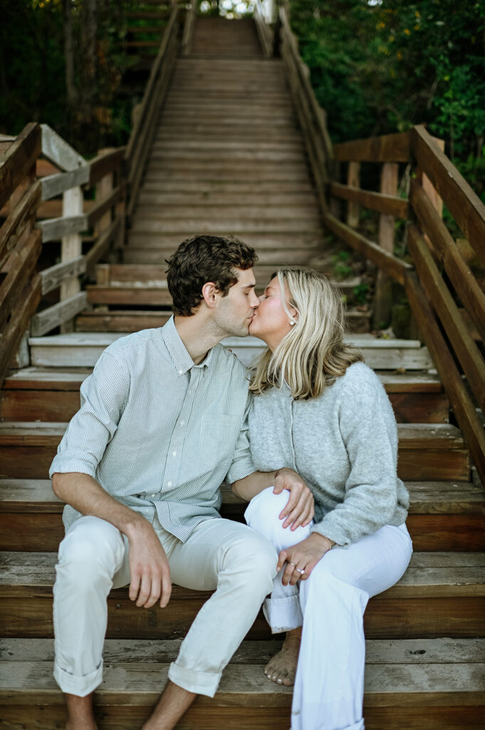 Couple kissing on beach stairs during their New Buffalo engagement photos