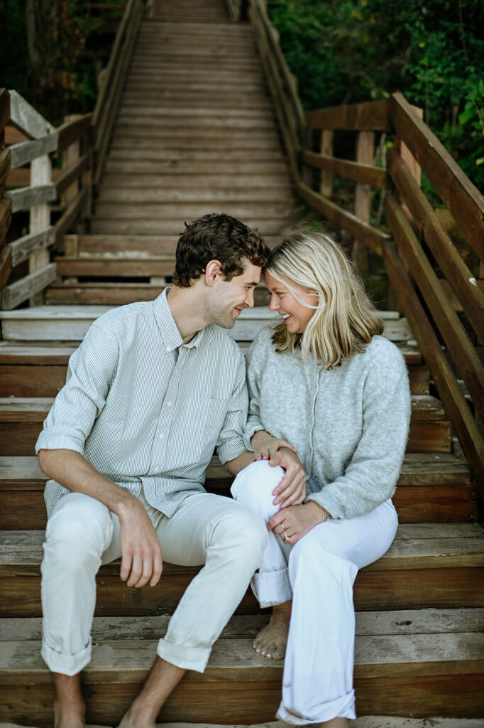 Man and woman smiling at each other on beach stairs