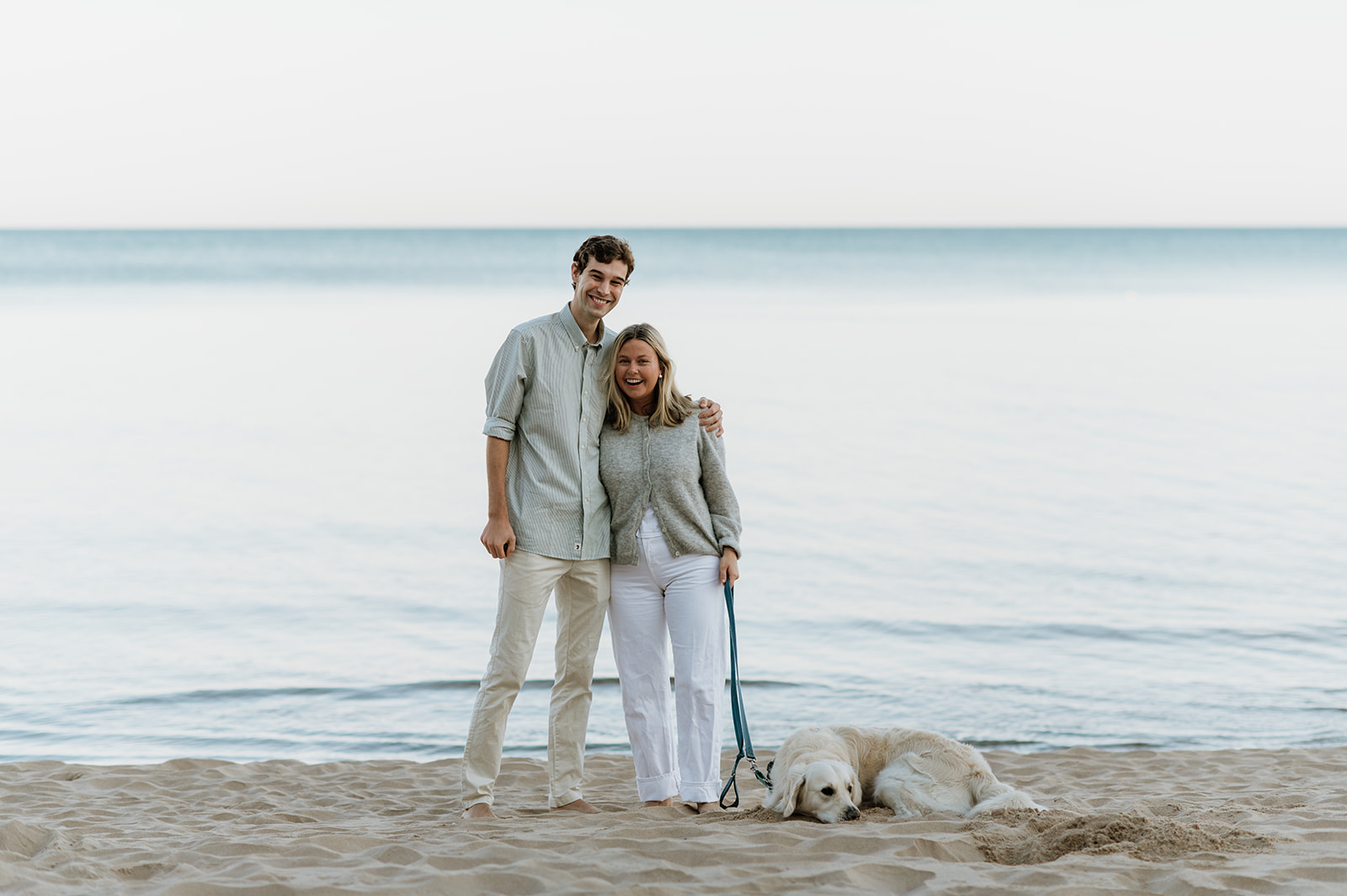 Man, woman and their dog on the beach after a Michigan surprise proposal