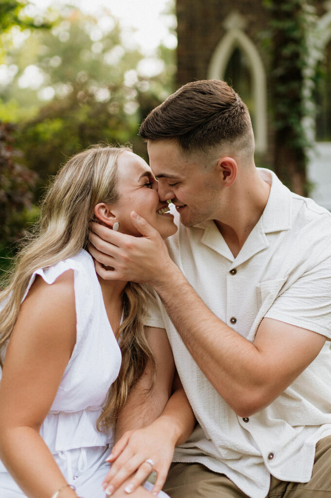 Couple laughing and going in for a kiss during their Hamstra Gardens engagement photos in Wheatfield, Indiana