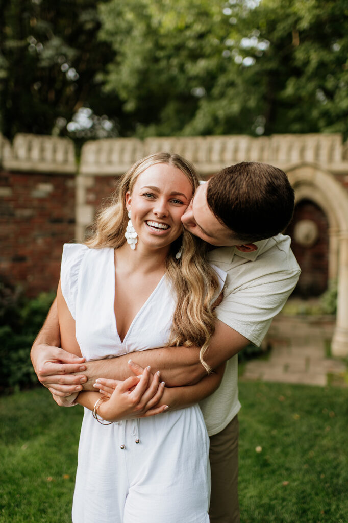 Man kissing his fiancé on the cheek during their outdoor engagement session