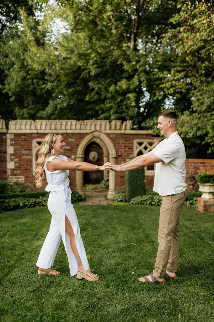 Couple holding hands and being playful during their garden engagement session